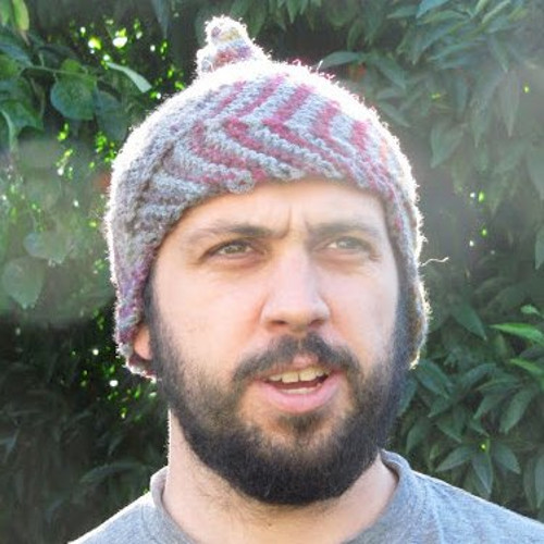 bearded man in a knit hat standing outside looking off into the distance