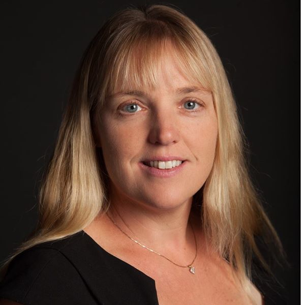 professional photo of a woman in a black shirt smiling for the camera in front of a black backdrop