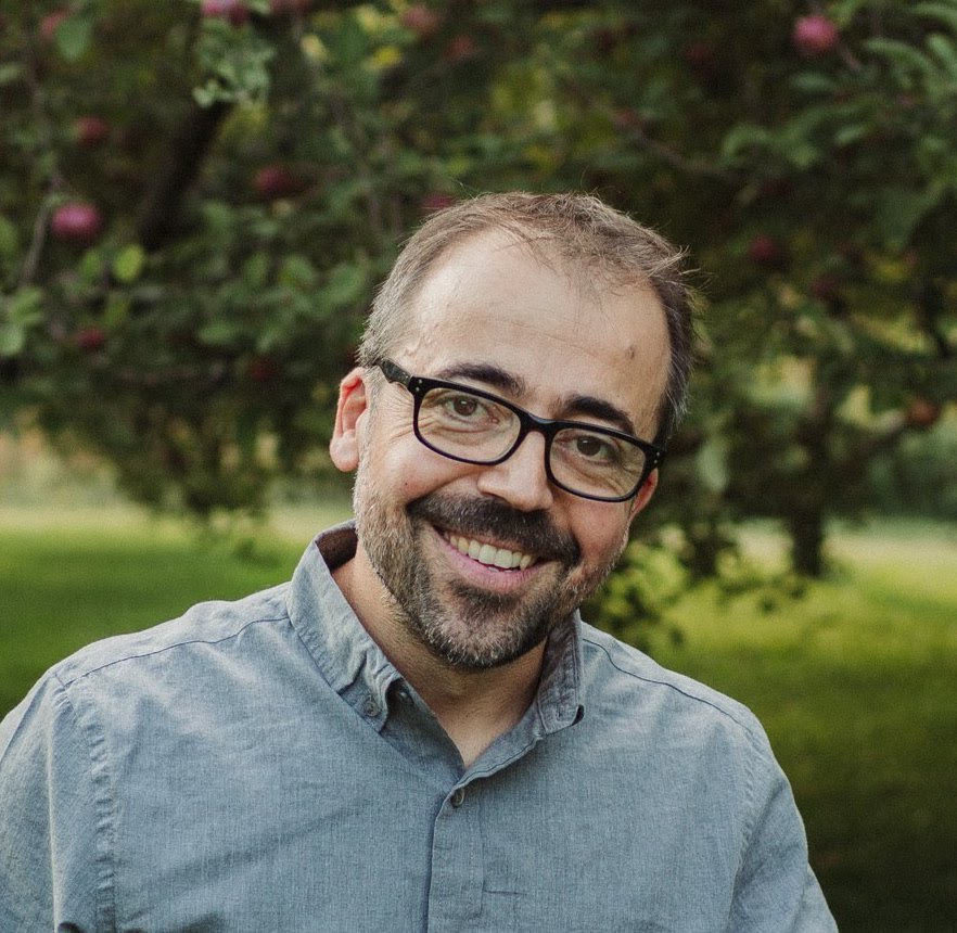 Man smiling at the camera with greenery in the background